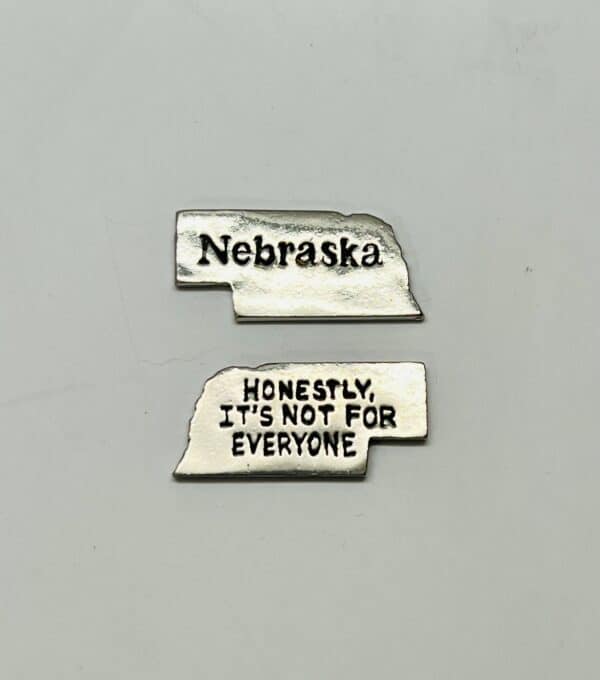Nebraska shaped metal pocket charm with Nebraska slogan "Honestly, it's not for everyone."